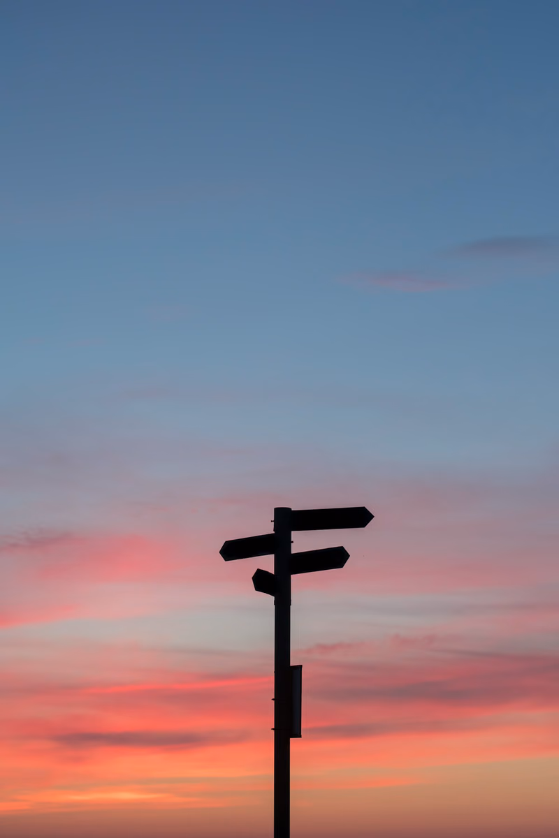 Wegweiser mit mehreren Richtungen bei Sonnenuntergang als Sinnbild für die Vertriebskanäle in der Baufinanzierung